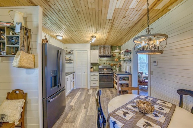 dining space with wood ceiling, a notable chandelier, wooden walls, and light wood-type flooring