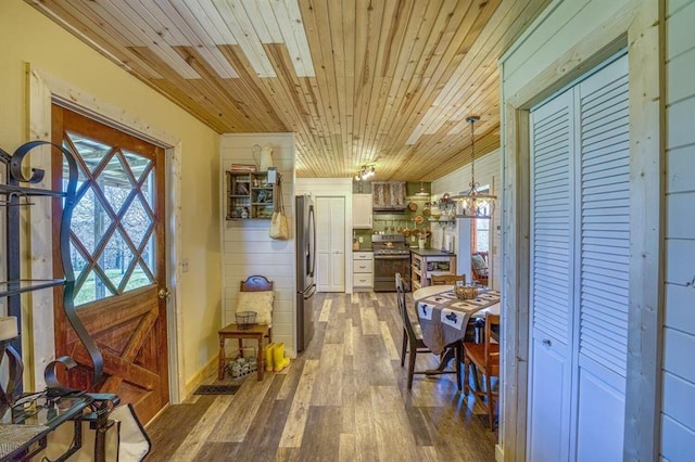 kitchen featuring appliances with stainless steel finishes, white cabinets, hanging light fixtures, hardwood / wood-style flooring, and wood ceiling