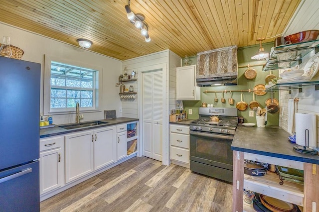 kitchen featuring sink, stainless steel gas range oven, white cabinetry, refrigerator, and wooden ceiling