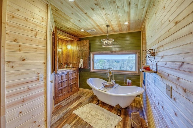 bathroom with hardwood / wood-style floors, vanity, a bath, wooden ceiling, and wood walls