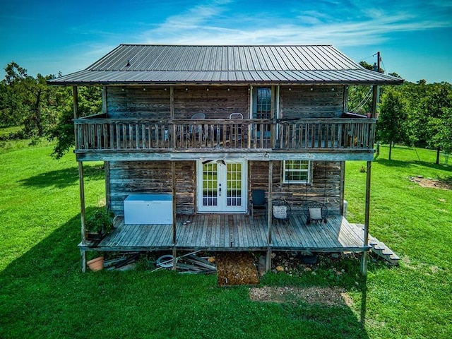 rear view of house featuring a balcony and a yard