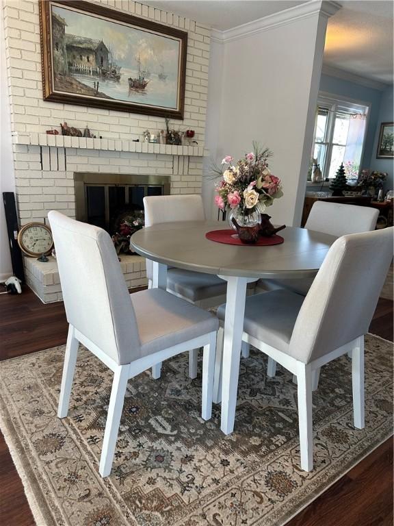 dining space with a fireplace, ornamental molding, and wood finished floors