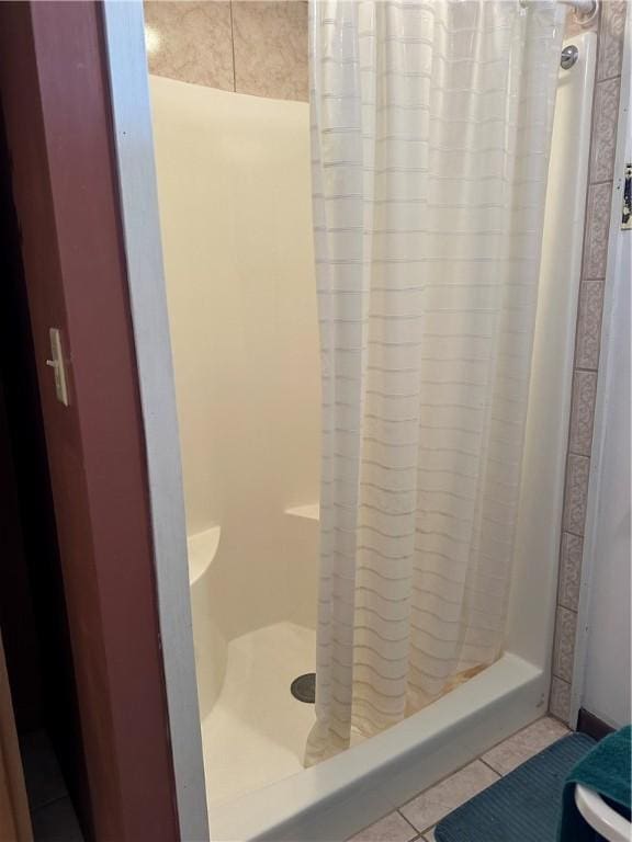 bathroom with a stall shower and tile patterned flooring