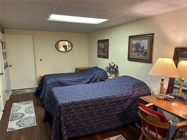 bedroom featuring concrete block wall and wood finished floors