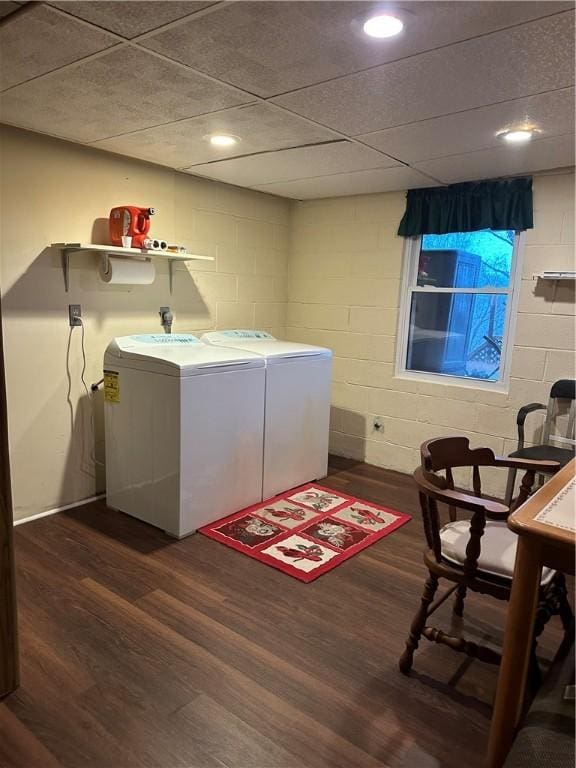 clothes washing area with laundry area, independent washer and dryer, dark wood finished floors, and concrete block wall