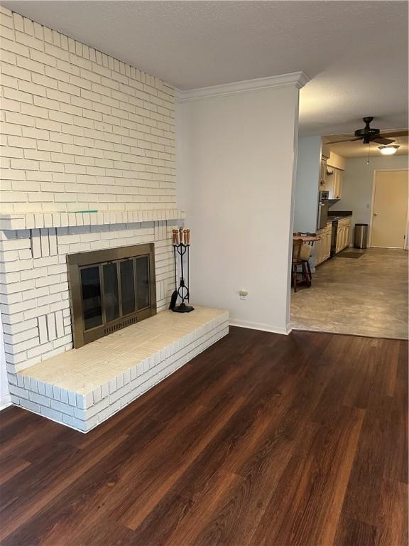 unfurnished living room with ceiling fan, a fireplace, wood finished floors, baseboards, and ornamental molding