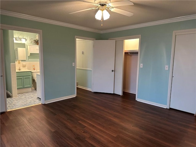 unfurnished bedroom featuring connected bathroom, dark wood-style flooring, a ceiling fan, baseboards, and crown molding