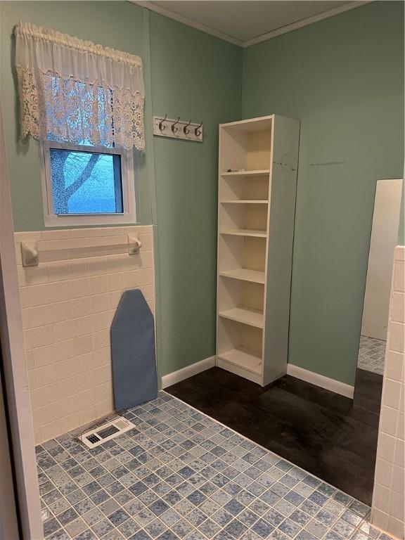 interior space featuring crown molding, tile walls, and baseboards