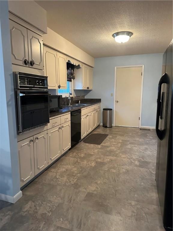 kitchen featuring dark countertops, a sink, a textured ceiling, black appliances, and baseboards