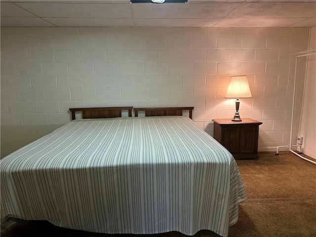 carpeted bedroom featuring concrete block wall