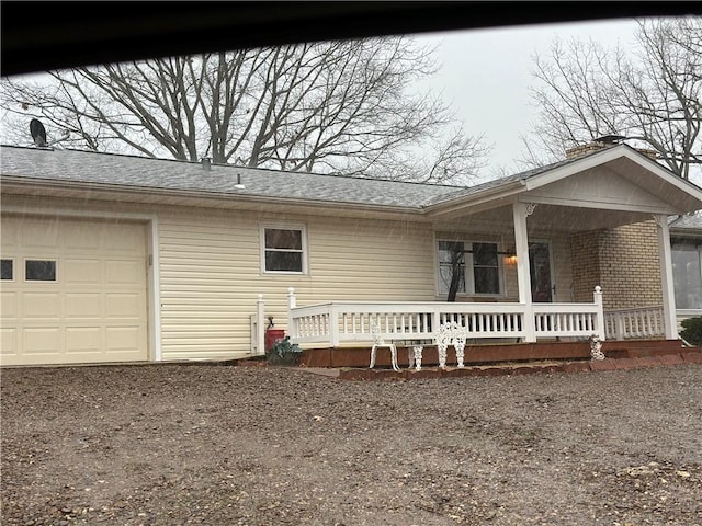 view of front of home with an attached garage, a shingled roof, a porch, and brick siding