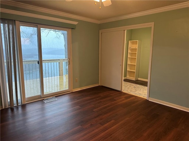 empty room featuring ornamental molding, a ceiling fan, baseboards, and dark wood-style floors