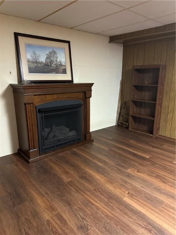 unfurnished living room featuring concrete block wall, a fireplace, and dark wood finished floors