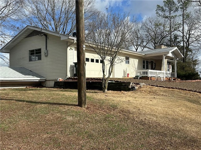 exterior space featuring covered porch, a lawn, a chimney, and an attached garage