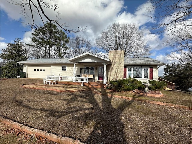 view of front of house featuring an attached garage, a chimney, and a porch