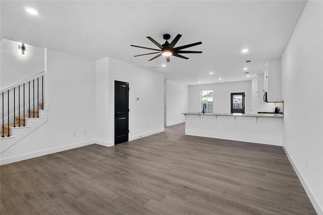 unfurnished living room featuring dark hardwood / wood-style floors and ceiling fan