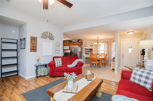 living room with light hardwood / wood-style flooring and ceiling fan with notable chandelier