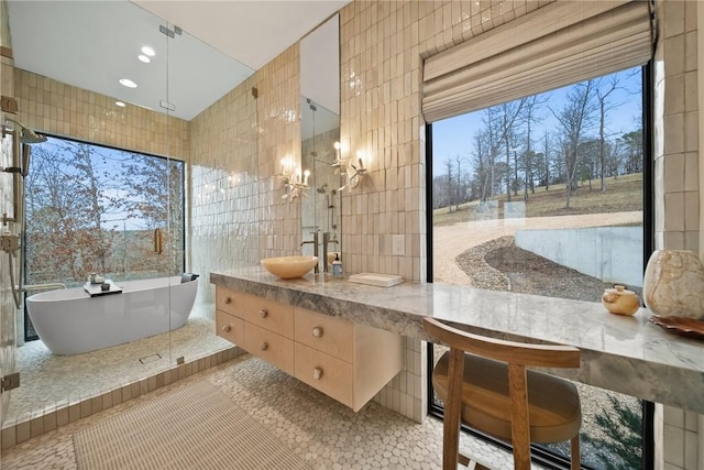 bathroom featuring a bath, vanity, tile patterned floors, and tile walls