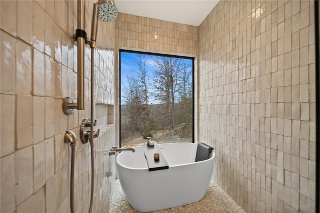 bathroom with tile patterned floors, a bathing tub, and tile walls