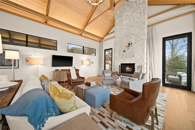 living room featuring light hardwood / wood-style flooring, high vaulted ceiling, beamed ceiling, a fireplace, and wood ceiling