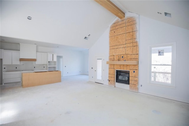 unfurnished living room with beamed ceiling, high vaulted ceiling, and a tile fireplace