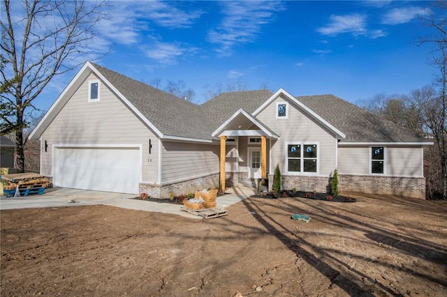 view of front of property with a shingled roof, brick siding, driveway, and an attached garage