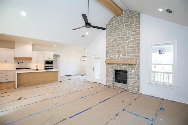 unfurnished living room featuring high vaulted ceiling, a sink, visible vents, a ceiling fan, and beamed ceiling