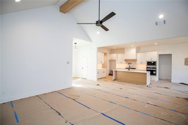 unfurnished living room featuring visible vents, ceiling fan, beamed ceiling, high vaulted ceiling, and a sink