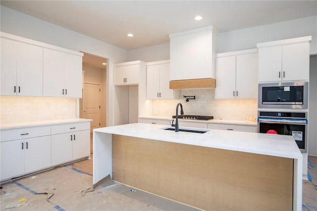 kitchen featuring white cabinets, backsplash, stainless steel appliances, and a sink