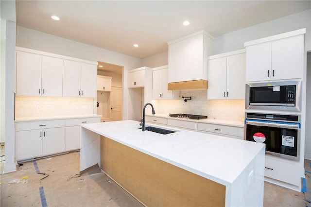 kitchen with oven, built in microwave, concrete floors, white cabinetry, and a sink