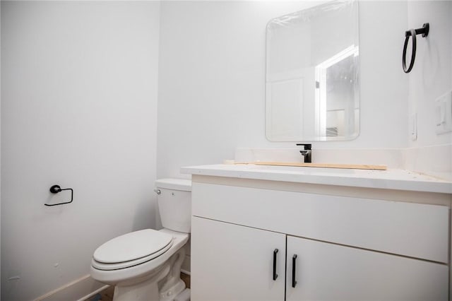 bathroom featuring toilet, baseboards, and vanity