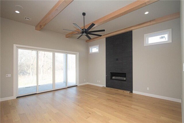 unfurnished living room with beam ceiling, light wood-type flooring, ceiling fan, and a tiled fireplace