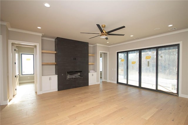 unfurnished living room featuring crown molding, ceiling fan, light wood-type flooring, built in features, and a large fireplace