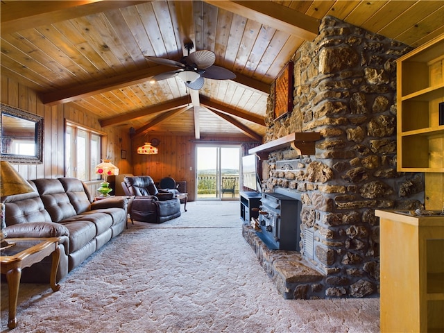 carpeted living room with ceiling fan, a wood stove, vaulted ceiling with beams, and wooden walls