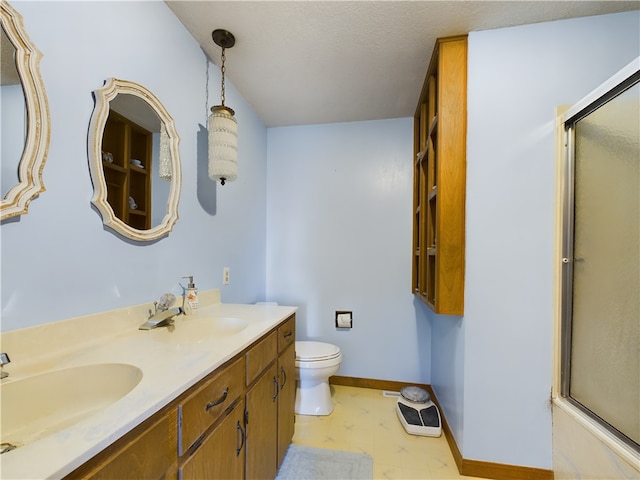 bathroom featuring toilet, vanity, and a shower with door