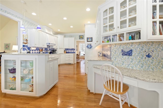 kitchen featuring backsplash, white cabinetry, hanging light fixtures, and light stone countertops