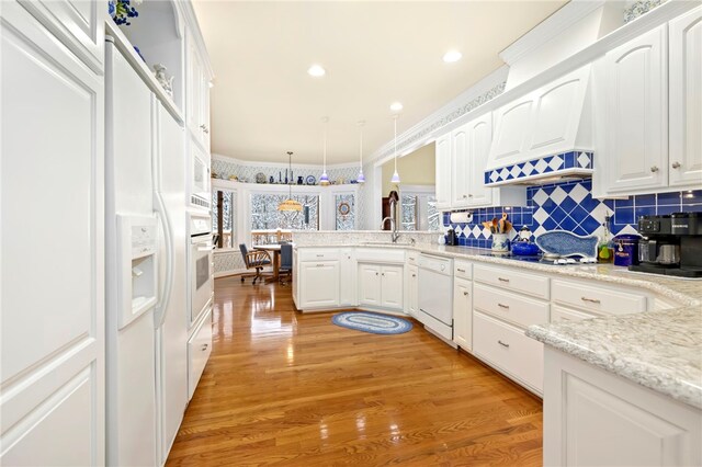 kitchen featuring white appliances, decorative light fixtures, white cabinetry, and light hardwood / wood-style floors