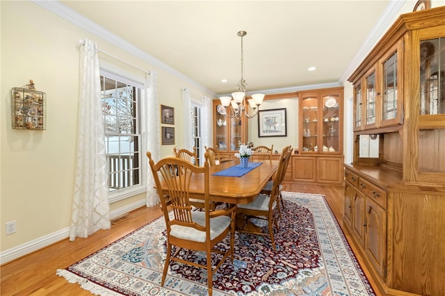 dining area with an inviting chandelier, ornamental molding, and light hardwood / wood-style flooring