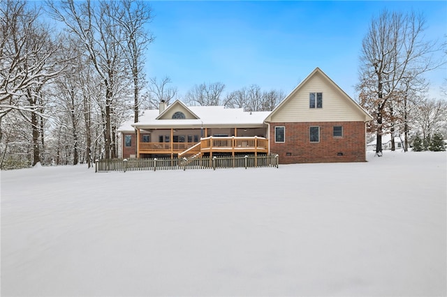 snow covered back of property featuring a deck