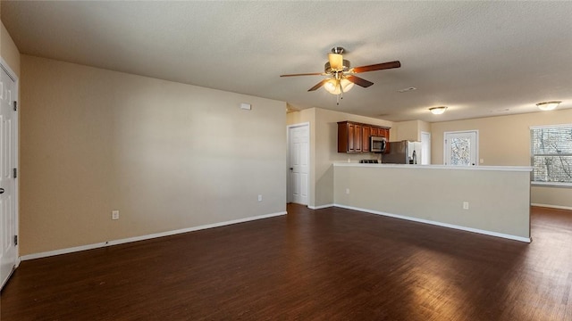 unfurnished living room with a textured ceiling, dark wood-type flooring, and ceiling fan