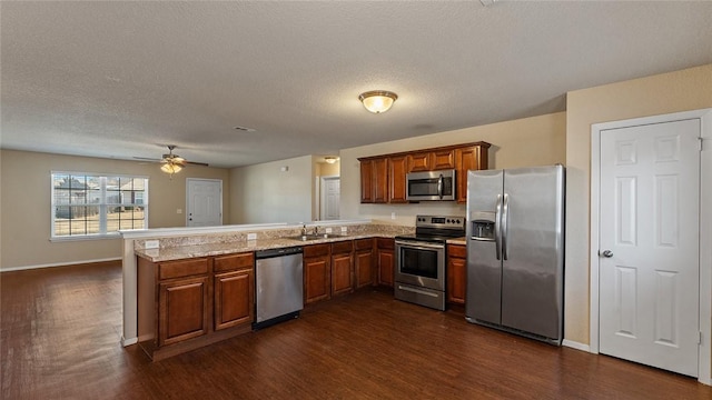 kitchen with ceiling fan, kitchen peninsula, dark hardwood / wood-style flooring, and stainless steel appliances