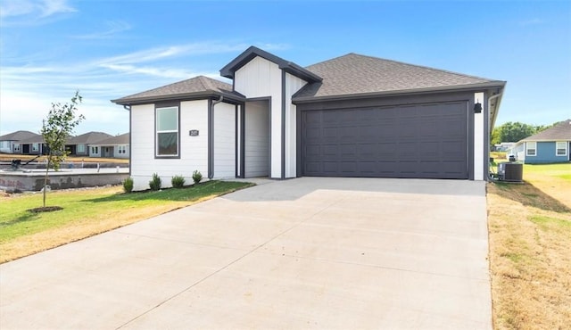 view of front of home featuring a front yard, a garage, and central AC unit