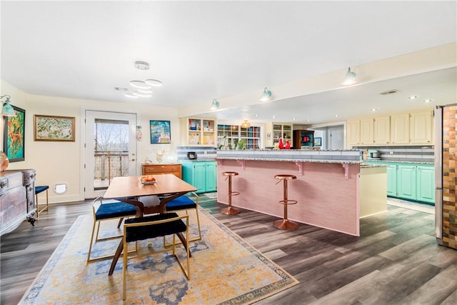 kitchen with a breakfast bar, stainless steel fridge, tasteful backsplash, a kitchen island, and dark hardwood / wood-style flooring