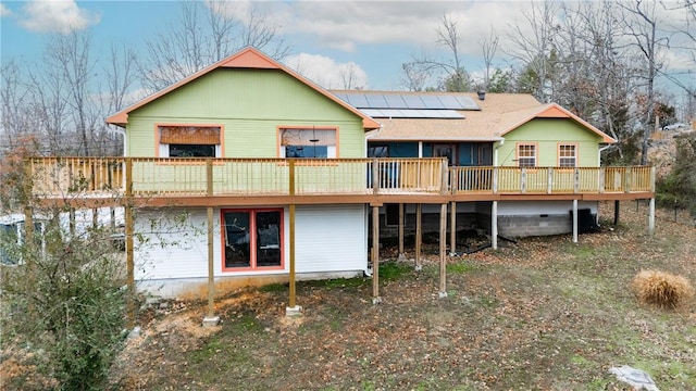 back of house featuring solar panels and a deck