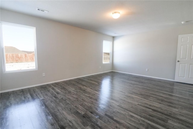 spare room with dark wood-type flooring and plenty of natural light