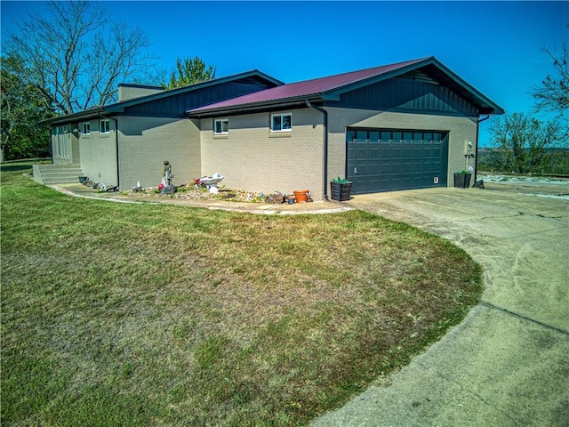 view of side of home with a garage, a yard, brick siding, and driveway