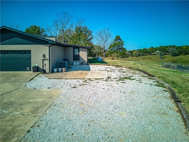 view of side of property with a garage, driveway, brick siding, and a yard