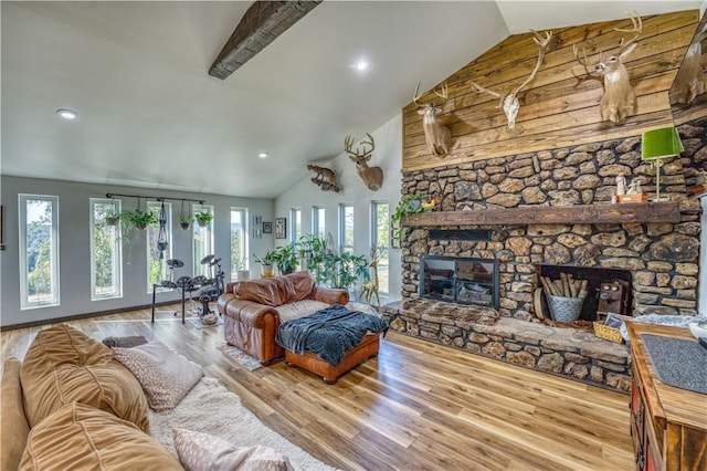 living room featuring recessed lighting, high vaulted ceiling, wood finished floors, and a stone fireplace