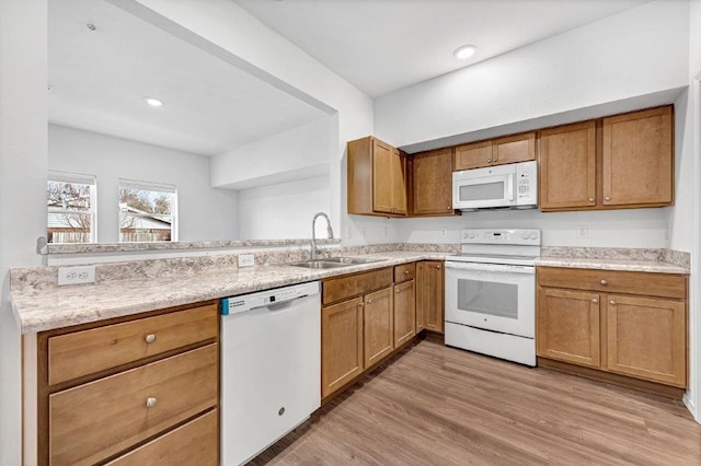 kitchen featuring white appliances, light wood-style flooring, brown cabinetry, and a sink