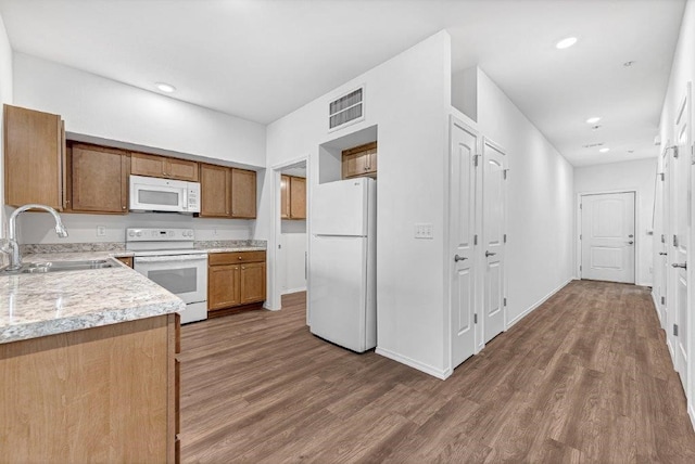 kitchen featuring visible vents, a sink, white appliances, light countertops, and dark wood-style flooring